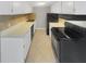 Galley kitchen with white cabinets, black appliances, and tile floor at 3541 Old Chamblee Tucker Rd # G, Atlanta, GA 30340
