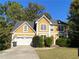 Two-story house with a yellow facade, white garage door, and landscaping at 1965 Tyler Trce, Lawrenceville, GA 30043