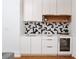 Modern wet bar with white cabinetry, black and white geometric tile backsplash and wine cooler at 1281 Avalon Ne Pl, Atlanta, GA 30306