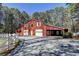 Red barn with garage doors, white fencing, and ample parking space at 2701 Stilesboro Nw Ln, Acworth, GA 30101