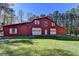Red barn with white garage doors nestled among trees at 2701 Stilesboro Nw Ln, Acworth, GA 30101