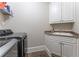 Bright laundry room with white cabinets, a utility sink, and a shelf at 3960 Carissa Trce, Cumming, GA 30040