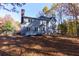 Back exterior of the house with a deck, surrounded by trees and a fenced yard at 2001 Towne Lake W Hls, Woodstock, GA 30189