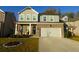 Two-story home with brick and siding, a two-car garage, and a landscaped front yard at 573 Auburn Crossing Dr, Auburn, GA 30011