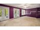 Large basement room with purple walls, carpeting, and French doors leading outside at 9140 N Links Dr, Covington, GA 30014