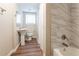 Clean bathroom with pedestal sink, bathtub, and marble-look tile at 3945 Shandra Way, Atlanta, GA 30349