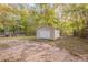Detached storage shed with a white garage door, located in a wooded backyard at 3730 Douglas Ridge Trl, Douglasville, GA 30135