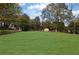 Large grassy backyard with mature trees and a partially visible shed at 2611 Kings Cir, Lawrenceville, GA 30044