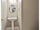 Small powder room with pedestal sink and round mirror at 401 Highway 279, Fayetteville, GA 30214