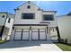 Two-story home with white brick exterior, three-car garage, and landscaping at 1883 Westfall Landing, Auburn, GA 30011