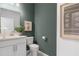 Charming bathroom with single vanity, toilet, and green accent wall at 386 Village Ln, Fairburn, GA 30213