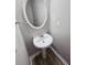 Small powder room with pedestal sink and oval mirror at 2654 Calumet Farm Ln, Snellville, GA 30039