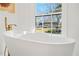 Modern bathtub with gold fixtures and a view at 1646 Tichenor Ct, Dunwoody, GA 30338