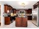 Modern kitchen featuring dark wood cabinets, granite island, and stainless steel appliances at 9154 Branch Valley Way, Roswell, GA 30076