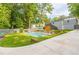 Landscaped backyard featuring a large pool, concrete driveway, and lush greenery at 1847 Walker Ave, College Park, GA 30337