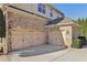 Three-car garage with carriage-style doors and brick and stone exterior at 2420 Bronze Ct, Cumming, GA 30041