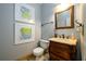 Elegant powder room with wood vanity, toilet, and framed art at 1379 Christiana Dr, Lawrenceville, GA 30043