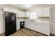 Bright kitchen with white cabinets, black appliances, and wood-look flooring at 2273 Hampton Locust Grove Rd, Locust Grove, GA 30248