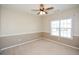Simple bedroom with neutral walls and carpet, featuring a ceiling fan and window at 138 Slippery Rock Ct, Villa Rica, GA 30180