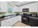 Modern kitchen with white cabinets and black appliances at 1874 Old Lost Mountain Rd, Powder Springs, GA 30127