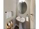Half bathroom with pedestal sink, oval mirror, and modern fixtures at 2108 Irvin Ct, Kennesaw, GA 30144