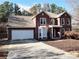 Charming two-story brick home with a white garage door, a covered entryway, and landscaping at 228 N Springs Way, Acworth, GA 30101