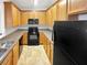Galley kitchen with light oak cabinets, black appliances, and granite countertops at 7512 Rutgers Cir, Fairburn, GA 30213