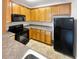 Kitchen with light oak cabinets, black appliances, and granite countertops at 7512 Rutgers Cir, Fairburn, GA 30213
