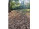 Large backyard with mature trees and fallen leaves at 1211 Golden Cir, Lilburn, GA 30047