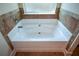 Garden tub with tile surround and window above at 168 Waypoint Dr, Stockbridge, GA 30281