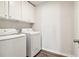 Bright laundry room with washer, dryer, and upper cabinets at 1462 Stephens View Dr, Loganville, GA 30052