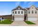 Two-story townhome with white and brick exterior, two-car garage, and landscaped lawn at 867 Eagle Avenue, Riverdale, GA 30247