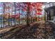 Lakefront yard with red tree, wooden swing, and dock at 510 Pine Lake Dr, Cumming, GA 30040