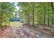 Gravel driveway entrance with a metal gate, trees, and a trailer in the distance at 1565 Dr Bramblett Rd, Cumming, GA 30028