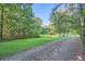 Gravel driveway lined with lush green trees and grass alongside at 1565 Dr Bramblett Rd, Cumming, GA 30028