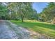 Gravel driveway next to a grassy yard with trees and bushes at 1565 Dr Bramblett Rd, Cumming, GA 30028