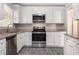 Modern kitchen with white cabinets, granite countertops, and stainless steel appliances at 2415 Plantation Dr, Atlanta, GA 30344