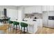 Modern white kitchen with an island, green bar stools, stainless steel appliances, and decorative backsplash at 1600 Cherry Hill Sw Ct, Conyers, GA 30094