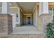 Covered front porch with brick columns and a gray door at 5732 Cypress Bluff Ln, Hoschton, GA 30548