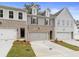 Three-unit townhome building, featuring brick and gray siding, two-car garages, and landscaped yards at 689 Sunstone Ln, Lawrenceville, GA 30043