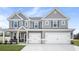Two story gray house with white accents, three car garage, and front porch at 1049 Bodega Loop, Locust Grove, GA 30248