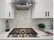 Gas cooktop with stainless steel range hood and modern backsplash at 4562 Spring St, Acworth, GA 30101