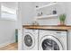 Bright laundry room with white washer and dryer and wooden shelf at 278 Patterson Ave, Atlanta, GA 30316