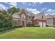 Brick two-story house with a three-car garage and manicured lawn at 2023 Ector Nw Ct, Kennesaw, GA 30152