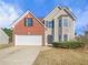 Two-story house with brick and beige siding, a white garage door, and landscaping at 585 Windsor Brook Ln, Lawrenceville, GA 30045