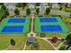 Aerial view of four well-maintained tennis courts with surrounding landscape at 8115 Lockslay Way, Suwanee, GA 30024