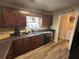 Kitchen features dark wood cabinets, granite countertops, and a view into laundry room at 350 Chestnut Dr, Covington, GA 30016