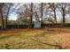 Spacious, fenced backyard with storage shed, mature trees, and scattered leaves at 5760 Lakeview Dr, Powder Springs, GA 30127