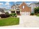 Brick two-story house with a three-car garage and landscaped front yard at 2910 Blake Towers Ln, Buford, GA 30519