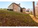 Backyard view of brick home, with trees and grassy slope at 1560 Tapestry Rdg, Lawrenceville, GA 30045
